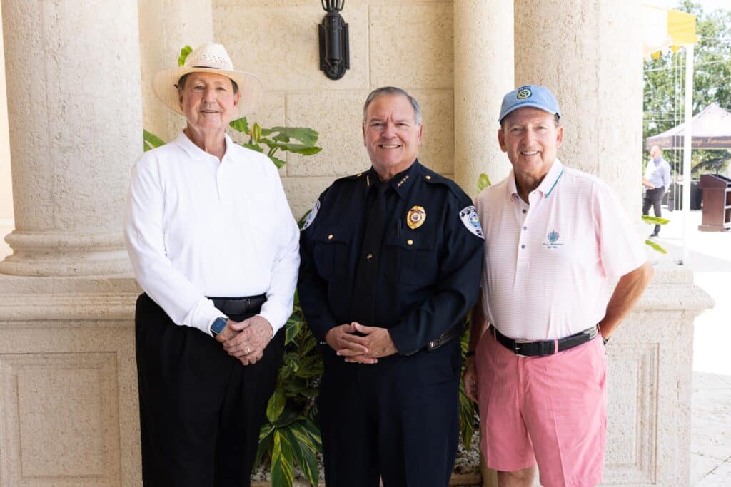 three men pose for picture man in the middle is in police uniform